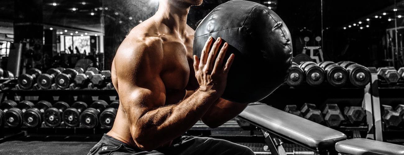 Svalnatý muž zvedá medicinbal.