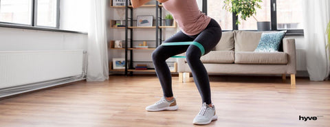 Žena cvičí doma s posilovací gumou.