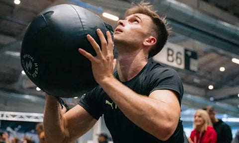 Muž cvičí s medicinbalem.