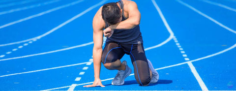 Muž po doběhnutí klečí na kolenou a otírá si pot z čela.
