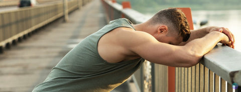 Muž odpočívá po sportu a opírá se na mostu.