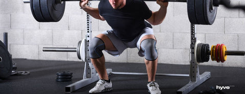 Muž dřepuje s těžkou činkou.