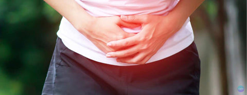 Žena se drží za bolestivé břicho.