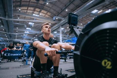 Sportovec při veslování na trenažéru během závodu HYROX.