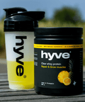 hyve clear whey protein citron–ananas a rozmíchaný nápoj v shakeru na venkovním dřevěném stole