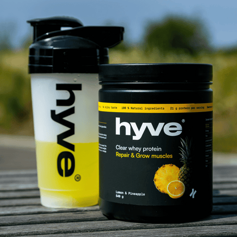 hyve clear whey protein citron–ananas a rozmíchaný nápoj v shakeru na venkovním dřevěném stole