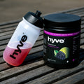 hyve Endurance Pro ostružina a limetka a bidon s růžovým nápojem na venkovním dřevěném stole