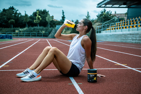 Atletka během pauzy pije iontový nápoj hyve hydration pro.