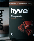 hyve Whey Protein čokoláda a shaker s čokoládovým proteinovým nápojem na venkovním stole