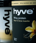 hyve Whey Protein Vanilla a shaker s vanilkovým proteinovým nápojem na venkovním stole