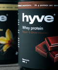 hyve Whey Protein Vanilla a hyve Whey protein Chocolate na dřevěném stole venku