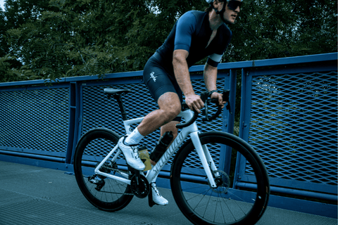 Detail cyklisty při cyklistickém tréninku, zaostřeno na nohy a řídítka.